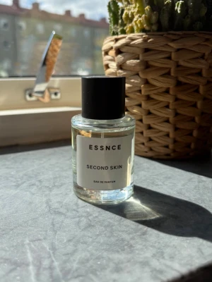 ESSNCE Second Skin Eau de Parfum - Minimalistisk parfymflaska från ESSNCE med doften Second Skin. Flaskan är genomskinlig med svart lock och vit etikett med svart text. Modern och stilren design som passar perfekt på parfymhyllan. Använd enstaka gång 