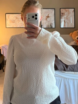 Vit strukturerad blus med puffärm - Säljer en vit blus med lång ärm och lätt puff vid axlarna. Blusen har en strukturerad, krinklad yta och rund halsringning. Passar perfekt till både jeans och kjol för en trendig look.