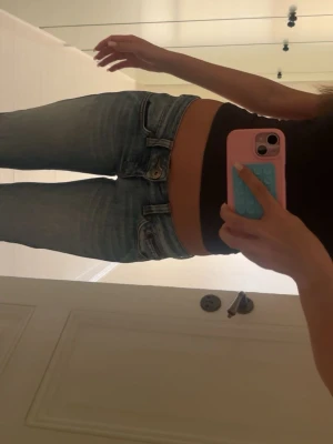 Ljusblå bootcut jeans låg midja - Säljer ett par ljusblå bootcut jeans med låg midja och klassisk femficksmodell. Jeansen har en snygg tvätt med lätt slitningar och raka ben som går ut lite nedtill. Perfekta till en avslappnad och trendig look. I storlek: W27, L32 