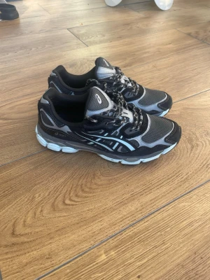 Svarta asics Gel - Snygga sneakers i svart och grått med vita detaljer och GEL-dämpad sula. Skorna har meshpaneler för bra ventilation, reflekterande detaljer och klassisk snörning. Perfekta för dig som gillar sportig stil och komfort. Andvända 1 gång 