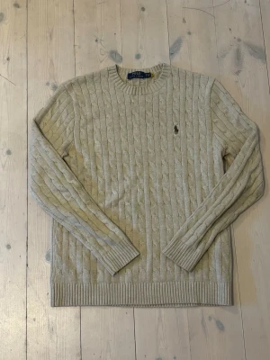 Beige kabelstickad tröja - Kabelstickad beige tröja från Polo Ralph Lauren med rund halsringning och ribbade muddar. Inte super använd. Dm gärna för mer :)