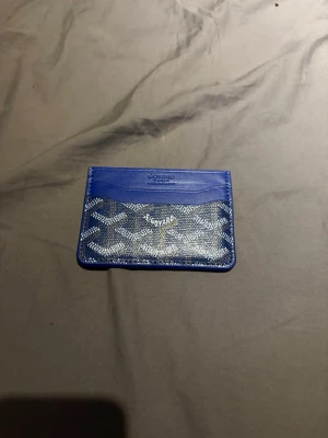 Blå kortfodral  - Snyggt blått kortfodral  med det klassiska mönstret i vitt och grått. Tillverkat i läder med plats för flera kort. Perfekt för dig som vill ha en stilren och exklusiv accessoar i fickan.