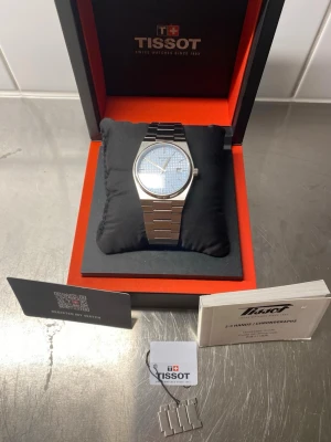 Tissot prx Powermatic 80 ljusblå urtavla full set - Säljer nu min mycket fina Tissot PRX Powermatic 80 i den populära 40 mm-versionen med den unika ice blue urtavlan. Klockan är en klassiker med en design som fungerar till det mesta.  Klockan fungerar utmärkt med det pålitliga powermatic 80 urverket. Den är i använt skick med normala bruksspår och några repor på länken som inte går att undvika vid vardagligt bruk. Klockan levereras full set med alla dess tillbehör som bilderna i annonsen visar. Nypris är 9000kr, hör av er vid funderingar!