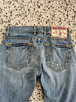 Baggy True Religion Jeans - Baggy true religion jeans i storlek 34. Köpta second hand med reva i knäet. Midjemått: 47cm. Innerbenslängden:82cm