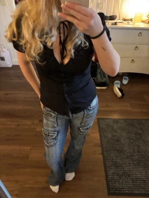 Blå jeans med fickdetaljer - Säljer ett par blå jeans med flera stora fickor och coola sömdetaljer. Jeansen har en avslappnad passform och lätt utsvängda ben. Perfekta för dig som gillar streetstyle och vill ha något unikt i garderoben. Köpte begagnade för något år sen så vet ej märket💗