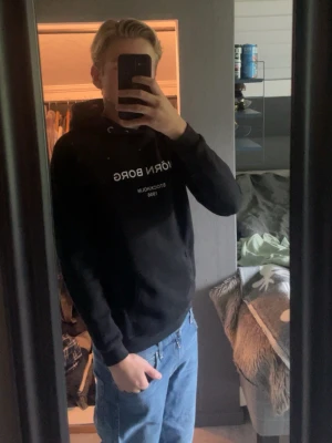 Svart hoodie från Björn Borg - Säljer en svart hoodie från Björn Borg med vit text på bröstet där det står 'BJÖRN BORG. Hoodien har huva med dragsko och en klassisk, avslappnad passform. Perfekt för dig som gillar stilrena och bekväma plagg.