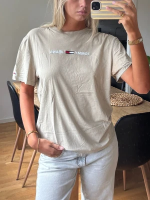 T-shirt  - Beige T-shirt med Tommy Hilfiger Jeans logga. 