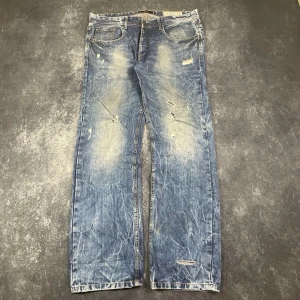 Y2K distressed vintagejeans för herr i storlek W38 L36 - Jeans för herr med Y2K-känsla och vintageinspirerad distressed look i storlek W38 L36. W/L är uppskattningar baserade på måtten.  Mått 📏 Midja: 49 cm Benslut: 22 cm Lår: 36 cm Totallängd: 116 cm Måtten hittas även på bilderna  Skickar produkten inom 24 timmar Genom att sätta ihop ett paket sparar du på priset och fraktkostnaderna Ytterligare information finns på min profil. 12-618. 