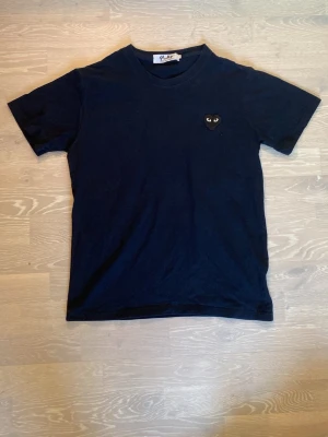 Mörkblå  COMME des GARÇONS T-shirt  - Mörkblå t-shirt från Comme des Garçons Play med det ikoniska svarta hjärtat broderat på bröstet. Klassisk rund hals och korta ärmar. Storleken är small. Priset kan diskuteras och skickar inom 24 Tim☺️💨