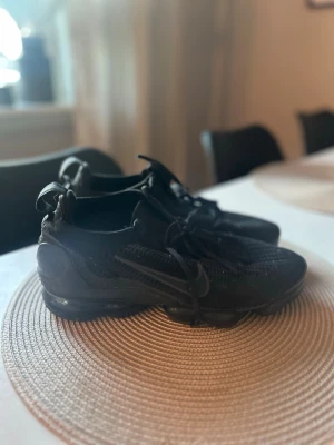 Nike vapormax - Säljer ett par helsvarta sneakers med stickad ovandel och snörning. Skorna har en sportig look med synlig sula och dragflik bak. Perfekta för dig som gillar stilrena och bekväma skor till vardags. Materialet är mesh-liknande och ger bra ventilation. 100% Äkta 