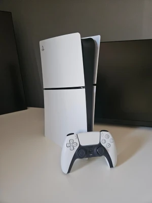 PlayStation 5 med DualSense-kontroller - PlayStation 5 konsol i vit och svart med futuristisk design och matchande DualSense-kontroll. Konsolen har en slimmad, stående form och är tillverkad i plast. Perfekt för gaming och nästa generations spelupplevelser. Helt ny ings problem kommer med två kontroller. Priset kan diskuteras