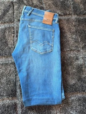 Replay anbass hyperflex - Snygga blå jeans från Replay med klassisk femficksmodell och ljus tvätt. Jeansen har raka ben, bälteshällor och detaljerade sömmar på bakfickan. Perfekta för en avslappnad och trendig stil. W 30 L 32