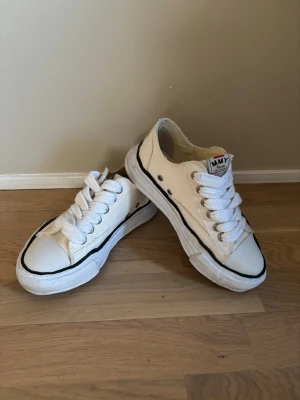 Maison Mihara Yasuhiro sneakers  - Säljer ett par vita sneakers från MMY med klassisk låg siluett. Skorna har grova vita snören, svart markerad kant runt sulan och slitna detaljer vid öppningen. Modellen ’Peterson’ och är i storlek 37. Nypris 3650kr