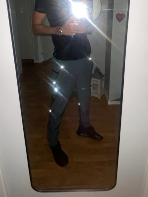 Primark byxor - Snygga mörkgrå mjukisbyxor med elastisk midja och dragsko. Byxorna har raka ben och praktiska fickor på sidorna. En vit logga finns tryckt på ena benet. Perfekta för en avslappnad och sportig stil. OBS! pris kan diskuteras.