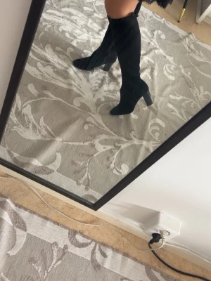 Svarta stövlar med klack - Säljer ett par svarta overknee stövlar med hög klack och rundad tå. Stövlarna har dragkedja på insidan och är gjorda i ett mjukt mockaliknande material. Snygg siluett som passar till kjol eller klänning.