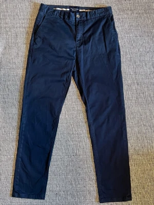 Marinblå chinos i slimfit från Bondelid - Snygga marinblå chinos i slimfit från Bondelid. Med klassiska detaljer som sidofickor och bakficka med knapp. Tillverkade i mjukt bomullstyg med bälteshällor i midjan. Perfekta för en clean och stilren look. Nypris 799kr