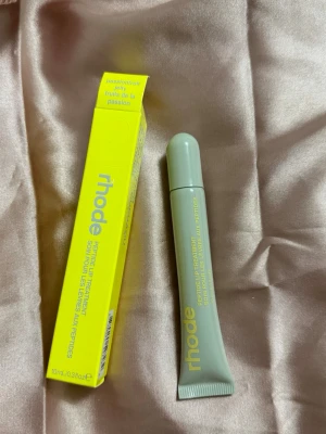 rhode peptide lip treatment passionfruit - Peptide Lip Treatment från rhode i smaken passionfruit. Kommer i en stilren, ljusgrå tub med gul text och tillhörande gul förpackning. Tuben rymmer 10 ml och är enkel att ta med i väskan. Perfekt för att återfukta och vårda läpparna med en fräsch doft av passionsfrukt.