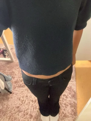 Mörkblå croppad stickad tröja - En mörkblå stickad tröja med croppad passform och korta ärmar. Tröjan har en enkel och stilren design, perfekt för lager-på-lager och passar till både jeans och kjol. Mjukt stickat material som känns bekvämt mot huden. Passar även 146/152.