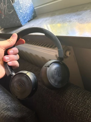 Svarta JBL on-ear hörlurar - OBS! Ej laddade och laddare följer inte med!! Säljer ett par svarta on-ear hörlurar från JBL med vadderade kåpor och justerbart huvudband. Hörlurarna har inbyggda knappar på sidan för enkel styrning av musik och samtal. Snygg och enkel design som passar perfekt till mobilen eller datorn.