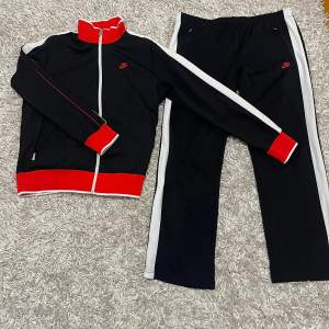 Säljer en helt ny limiterad vintage tracksuit från Nike med röda detaljer och vit dragkedja. Perfekt för träning eller en avslappnad stil. Jackan har långa ärmar och en hög krage för extra komfort. Passar bra till både höst och vår.