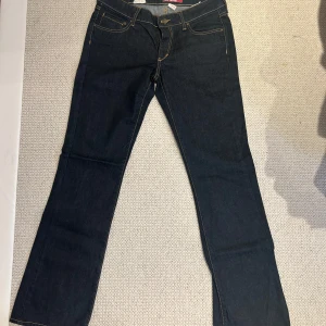 Bootcut midwaist jeans - Säljer ett par mörkblå jeans från & denim i storlek 30/32. De är bootcut/flared och medelhög i midjan. De har kontrastsömmar och bakfickor med knappar. Perfekta för både vardag och fest! 🕺