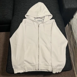 Vit hoodie från Weekday - Säljer en stilren vit hoodie från Weekday i storlek XS. Hoodien är i bra skick och passar till alla säsonger. Hoosiers är lite liten på modellen då han normalt vid använder M