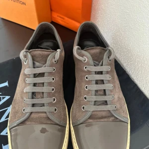 Grå sneakers från Lanvin - Säljer mina Lanvins eftersom jag inte använder dom. skick 8,5 knappt använda. Dustbag följer med. Mer bilder kan skickas, vid snabb affär kan jag gå ner i pris.