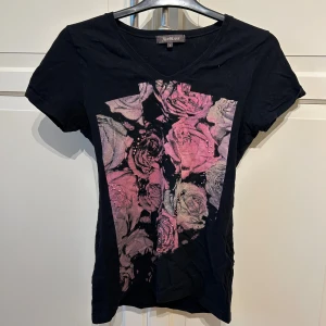 Svart t-shirt med blommönster från Alice Bizous - Snygg svart t-shirt från Alice Bizous i storlek S. Tröjan är kvinnosyd och ger en tajt och snygg siluett💕
