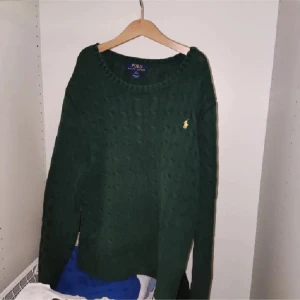 Grön stickad tröja från Polo Ralph Lauren - Säljer en snygg grön stickad tröja från Polo Ralph Lauren. Den har ett klassiskt kabelstickat mönster och den ikoniska loggan broderad på bröstet. Perfekt för kyliga dagar och passar både till vardags och lite finare tillfällen. Supermysig och stilren! 🍃