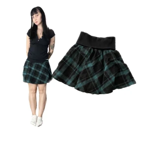 Rutig kjol i grönt och svart - Snygg rutig kjol i grönt och svart med en bred svart midja. Kjolen har en kort längd och är superbekväm att bära.