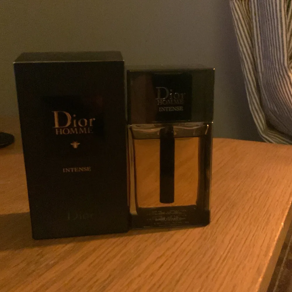 Säljer en flaska Dior Homme Intense Eau de Parfum. Flaskan är elegant med en svart kork och en stilren design. Parfymen har en djup och intensiv doft, perfekt för speciella tillfällen. Flaskan är nästan full och kommer i originalförpackning. Perfekt för dig som vill ha en lyxig och maskulin doft. den är också 100ml i storlek. Parfym.