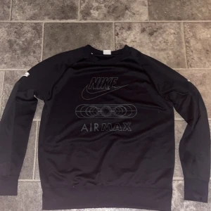 Svart Nike Air Max tröja - Säljer en svart Nike Air Max tröja i bra skick. Den har ett stort tryck på framsidan med Nike-loggan och Air Max-design. Perfekt för en casual look eller träning. Tröjan har långa ärmar och är superbekväm. Passar perfekt till jeans eller träningsbyxor! Pris kan diskuteras