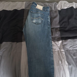 Blå jeans från Jacob Cohen - Säljer ett par snygga blå jeans från Jacob Cohen. De har en klassisk femficksdesign med en diskret logga på bakfickan. Perfekta för både vardag och fest! Otroligt bra pris!