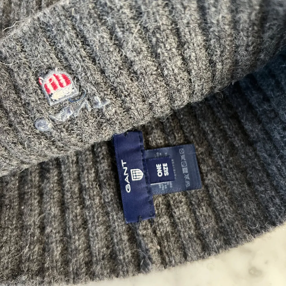 Säljer en snygg grå ribbad mössa från GANT i ull. Den är i one size och har en liten broderad logga på sidan. Perfekt för att hålla sig varm under höst och vinter. Mössan är i mycket bra skick och redo för nya äventyr!. Accessoarer.