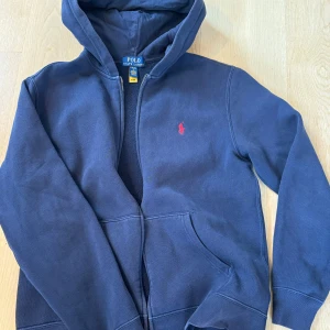 Ralph Lauren fleece zip hoodie 14-16 år - Fin hoodie som använts en handfull gånger. Mjuk bortstad insida. Strl 14-16 år (L)  men något liten i storleken. Inköpt i våras hos Kids Brand Store för 1195 kr.