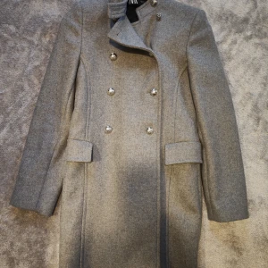 Zara kappa grå stl Small  - Grå dubbelknäppt kappa från Zara stl Small. Använd ca 10 gånger och är i skick som ny.