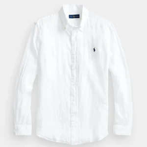 Vit linneskjorta från Ralph Lauren - Säljer en snygg vit linneskjorta från Ralph Lauren. Skjortan har en klassisk krage och knappar framtill. Den är långärmad och har en broderad blå logga på bröstet. Perfekt för både vardag och fest! Skjortan är slimfit! Nypris 2000kr+ mitt pris 600kr