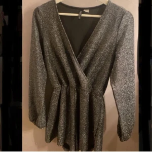 Glittrig playsuit - Snygg glittrig omlottPLAYSUIT. Perfekt till nyår! Finns en knapp på insidan för att ”stänga”