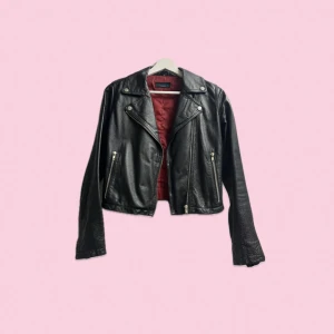 Svart skinnjacka bikermodell - Säljer en snygg svart skinnjacka i mycket bra skick. Jackan har en klassisk bikerstil med knappar på kragen. Storlek 34. Dragkedja framtill och på ärmarna. 