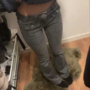 Grå jeans med fickdetaljer - Säljer ett par grå jeans från Kappahl i bra skick. De har en tight passform och är lågmidjade med snygga fickdetaljer fram. 