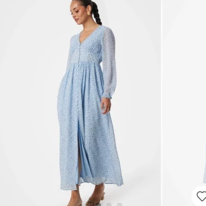 Blommig långklänning i ljusblått - Superfin långklänning i ljusblått med små blommor. Den har en v-ringad hals och knappar framtill. Ärmarna är långa och lite transparenta. Använd 1 gång