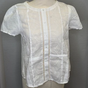 Vit blus - Vi säljer en super gullig blus , som aldrig är använd. Prislapp sitter kvar. Det är ett fint mönster tillsammans med några knappar. 