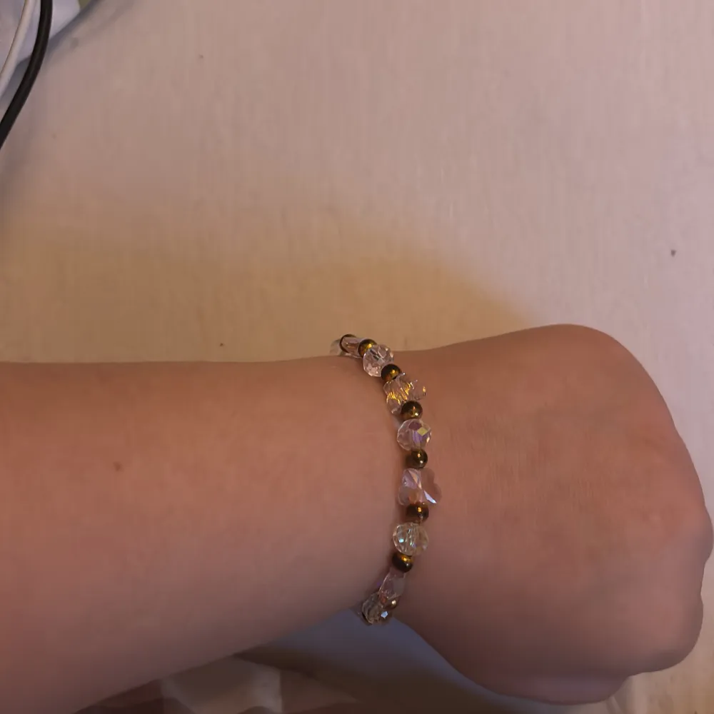 Säljer ett superfint armband med glittriga pärlor i olika färger. Pärlorna är genomskinliga med en regnbågsskimrande effekt och små guldiga pärlor emellan. Perfekt för att ge lite extra bling till din outfit! Passar bra till både vardag och fest.. Accessoarer.