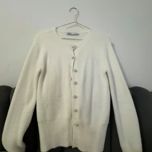 Vit kofta från Zara - Säljer en superfin vit kofta från Zara i storlek M. Den är i mycket bra skick och har jätte fina pärlknappar. Aldrig använd pågrund av storleken. 