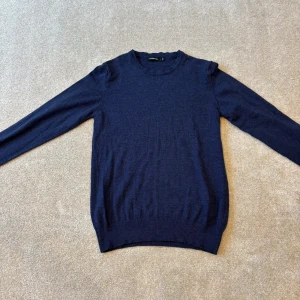 J.Lindeberg crewneck - Säljer en stilren mörkblå tröja med rund halsringning. Tröjan har långa ärmar och ribbade muddar vid ärmslut och nederkant. Perfekt för en klassisk look.