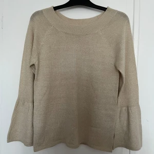 Beige blus från KappAhl - Säljer en stilren beige blus med guld detaljer från KappAhl i storlek M. Långa ärmar med en lätt volangdetalj vid ärmsluten. Perfekt för en avslappnad och elegant look. Passar både bra till fest och vardag 🤩