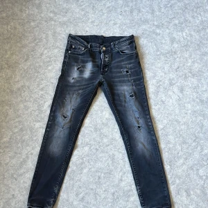 Svarta jeans från Dsquared2 - Snygga svarta jeans från Dsquared2 med slitna detaljer och en cool tvätt. De har en klassisk femficksdesign och knappgylf. Perfekta för en trendig look.