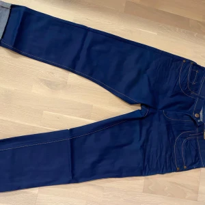 Mörkblå jeans från Beyrut - Snygga mörkblå jeans från Beyrut med klassisk femficksdesign och kontrasterande sömmar. Jeansen har en rak passform och är perfekta för en stilren look. Märkeslappen i brunt läder ger en extra touch av stil. Använda ytterst lite.