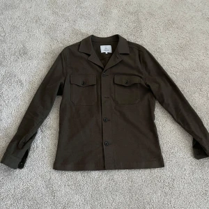 Olivgrön overshirt från Arket - Säljer nu denna overshirt från märket ”Bläck/Arket” i storlek S, den är i väldigt bra skick. fråga gärna om du undrar något. 