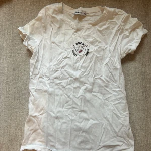 Vit t-shirt med tryck  - Säljer en vit t-shirt med ett coolt tryck av två händer och texten 'Good Vibes'. T-shirten är kortärmad och gjord i mjukt bomullsmaterial. Perfekt för en avslappnad stil! 